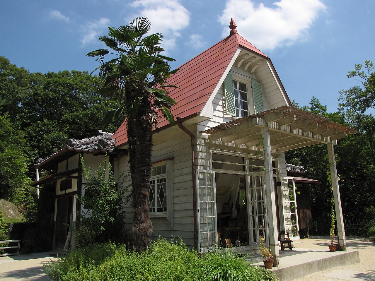 Maison de Satsuki et Mei : bois clair, toit rouge, portes ouvertes sur le jardin.